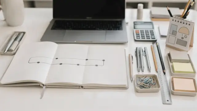 Arbeitsplatz mit Laptop, Kalender und Notizen zur Umsetzung einer Geschäftsidee und zum Gründungsstart