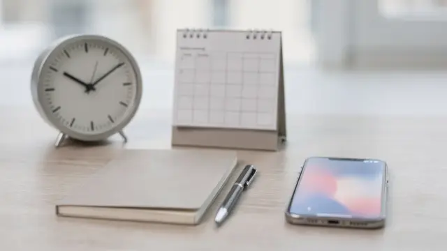 Kalender, Uhr und Smartphone auf Schreibtisch zum Thema Kommunikationszeiten festlegen