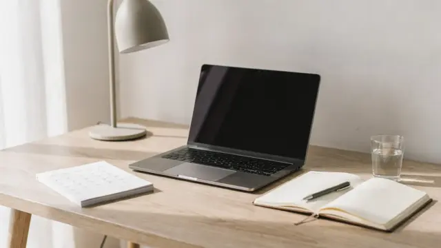 Aufgeräumter Homeoffice-Arbeitsplatz mit Laptop, Notizbuch und Kalender zur besseren Konzentration